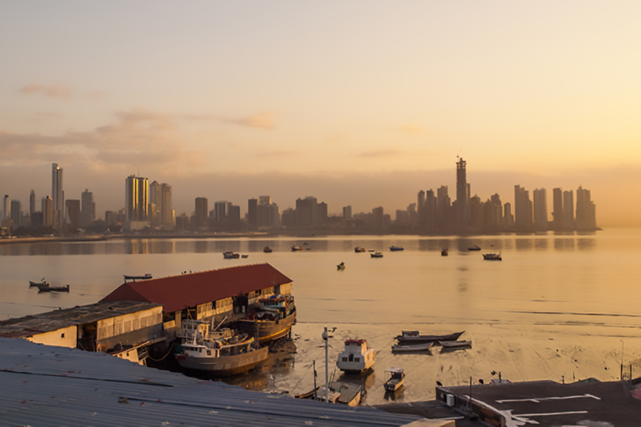 The sun sets over the Panama Bay with the city skyline in the background